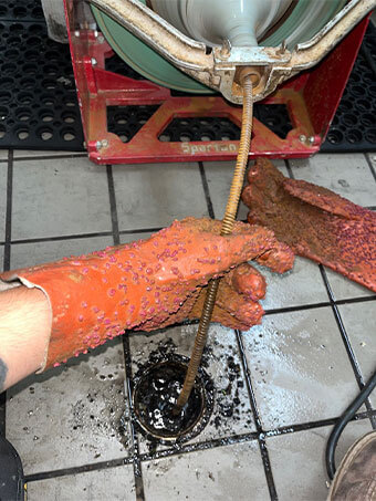 Drain-cleaning machine cable being fed into a floor drain