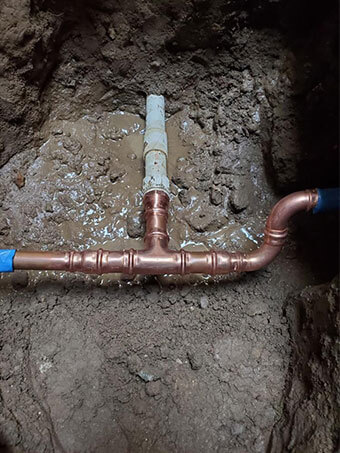 New copper line with a tee and press fittings in an open trench