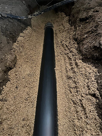 New pipe bedded in sand along an excavated trench